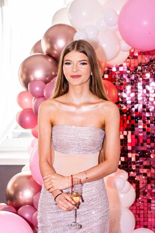 Jubilatka na tle różowej ścianki z balonami